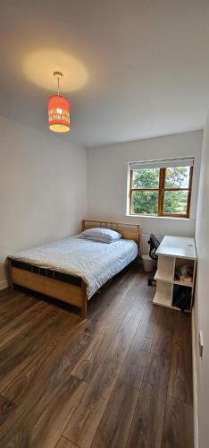 a bedroom with a bed and a desk and a window at The Nest in Summerseat