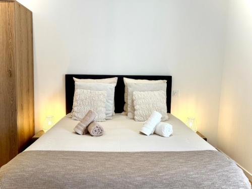 Un dormitorio con una cama con almohadas blancas. en Les Arches d'Or - Loft d'Exception avec Jacouzzi - 3 Suites - Grande Terrasse - Vue Théâtre Antique - Centre-Ville, en Orange
