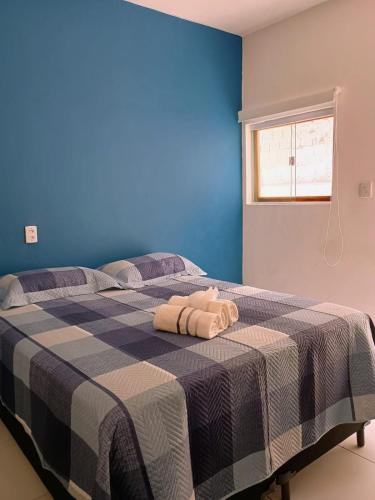 a blue bedroom with a bed with two towels on it at Suíte no Barra Mar in Barra de São Miguel