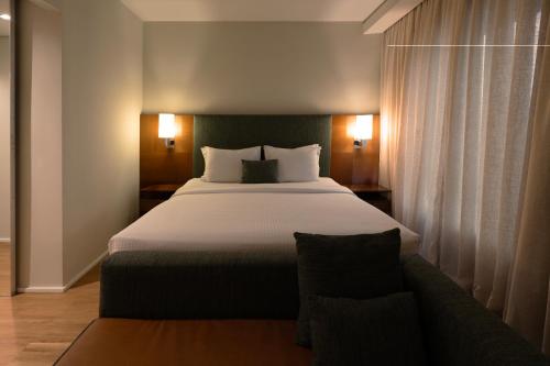 a bedroom with a large bed and a couch at Estanplaza Berrini in Sao Paulo