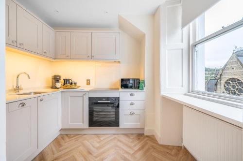a kitchen with white cabinets and a window at Romantic Getaway Apartment in Central Bath in Bath