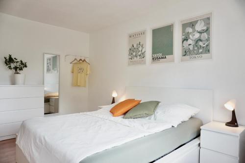 a white bedroom with a large bed with white sheets at NEU Gemütliche Wohnung für max 5 Personen mit Balkon nähe Mosel mit Blick auf die Weinberge in Koblenz
