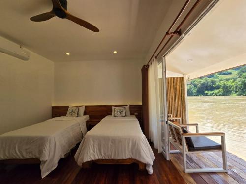 two beds in a room with a view of the water at Ou river house, deluxe in Nongkhiaw