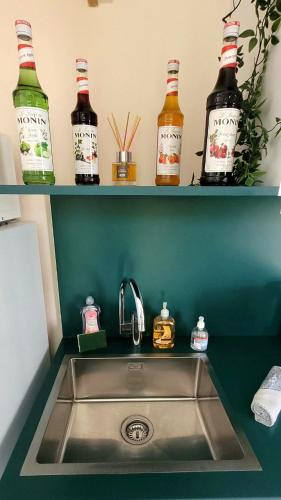 a kitchen sink with bottles on shelves above it at Le Cercle de Victoria stationnement privé petit déjeuner compris in Bourges