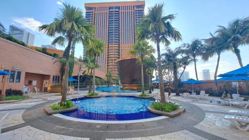 a large swimming pool with palm trees and a tall building at Signature Apartment Berjaya Times square Bukit Bintang in Kuala Lumpur