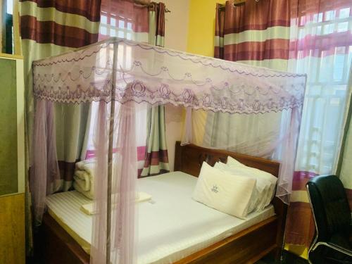 a bedroom with a canopy bed and curtains at Doreen Executive Inn in Morogoro