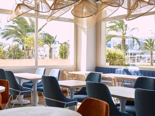 a restaurant with tables and chairs and windows at Ibis Elche in Elche