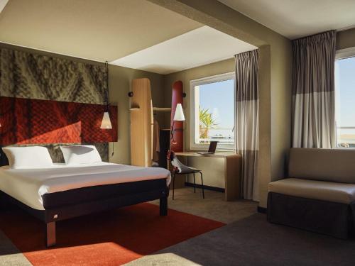 a hotel room with a bed and a chair at ibis La Ciotat in La Ciotat