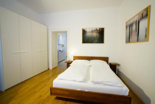 a bedroom with a bed with white sheets at Schlossquadrat Apartment 17 in Vienna
