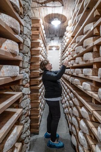 a woman is standing in front of a wall of logs at Locanda Del Mulino in Pamparato