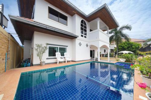 a villa with a swimming pool in front of a house at 5 bedroom pool villa quiet beach in Na Jomtien