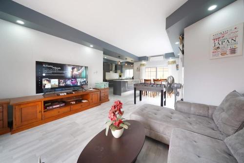 a living room with a couch and a tv and a table at 5 bedroom pool villa quiet beach in Na Jomtien