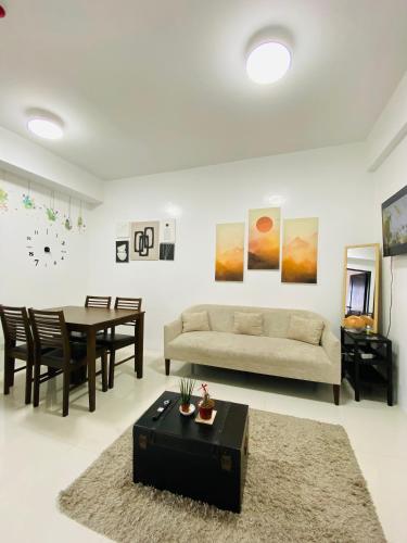 una sala de estar con un sofá y una mesa en 2-Bedroom Ladera Suites, en Baguio