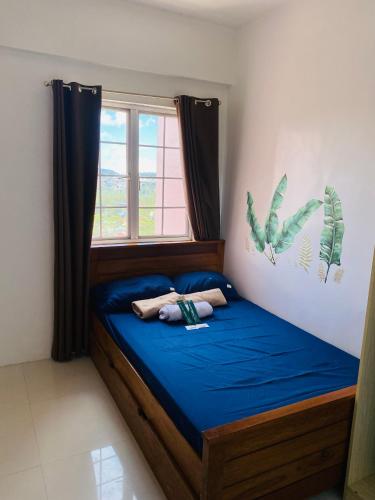Un dormitorio con una cama con sábanas azules y una ventana. en 2-Bedroom Ladera Suites, en Baguio