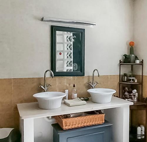un bagno con due lavandini e uno specchio di KAZ PANORAMA Luxe Créole Piscine et Terrasse Vue Panoramique Océan Fruits du Jardin Parapentes a Saint-Leu