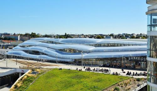 a large building with blue roofs and a grass field at Auréa - Elégant Duplex Rennes in Rennes