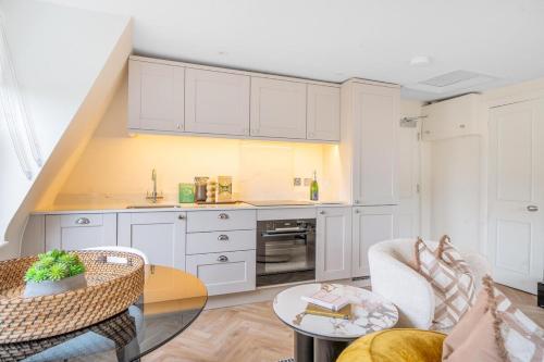 una cucina con armadi bianchi e tavolo in vetro di Boutique Bath Apartment, Minutes from Shops & Spas a Bath