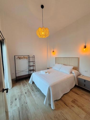 a bedroom with a white bed and a chandelier at Complejo turístico en Trebujena by Villamya in Trebujena