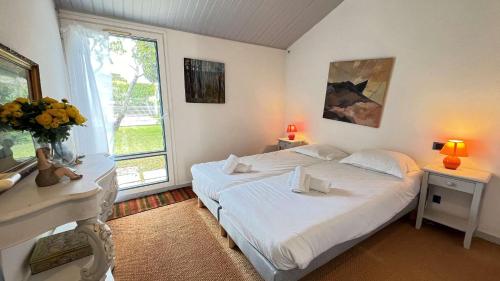 ein Schlafzimmer mit zwei Betten und einem Fenster in der Unterkunft Jolie maison avec jardin, piscine et parking in Sainte-Marie-de-Ré