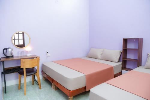 a room with two beds and a desk and a mirror at An house Ninh Binh in Ninh Binh