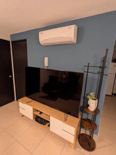 a living room with a flat screen tv and a air conditioner at Departamento cerca del Zocalo y aeropuerto in Mexico City
