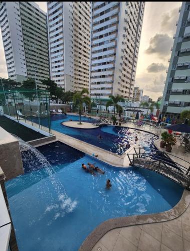 ein großes Schwimmbecken mit Menschen darin und hohen Gebäuden in der Unterkunft Apartamento à beira mar no Janga-Pe in Paulista