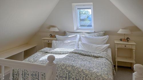 a bedroom with a white bed with pillows and a window at Heefwai in Morsum
