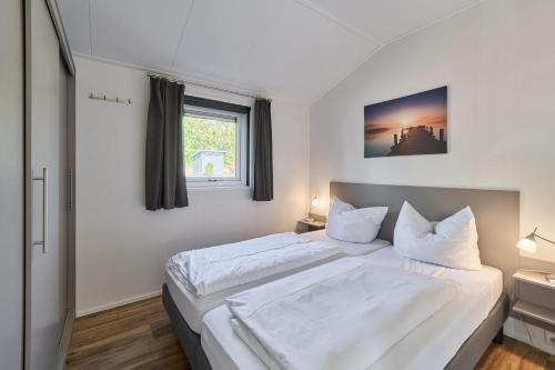 una camera da letto con un grande letto bianco con una finestra di Süsel Seeparx Ferienhaus Seezauber a Süsel