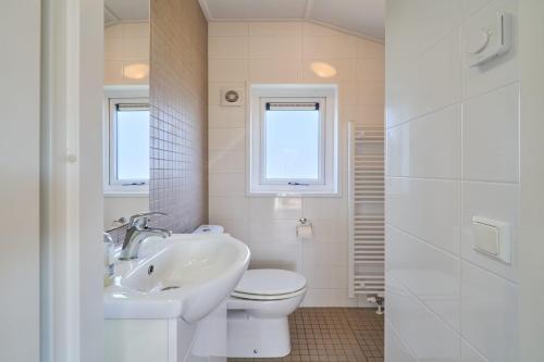 un bagno bianco con un water e un lavandino di Süsel Seeparx Ferienhaus Seezauber a Süsel