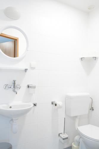 a white bathroom with a sink and a toilet at Kompleks Wypoczynkowo-Konferencyjny Mazur-Syrenka in Krutyń
