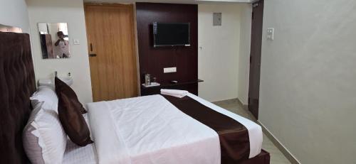 een slaapkamer met een bed en een televisie. bij Hotel AMR Residency in Tiruchirappalli