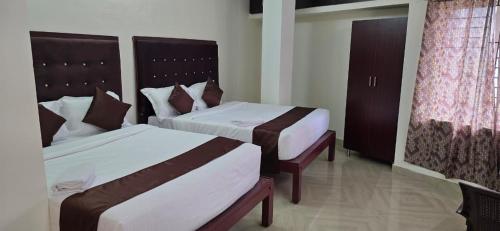 een hotelkamer met twee bedden en een raam bij Hotel AMR Residency in Tiruchirappalli