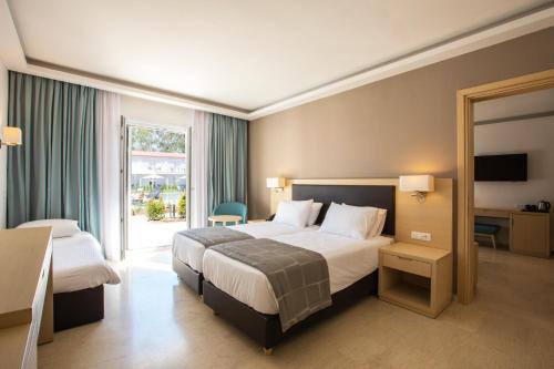 a hotel room with two beds and a window at Paleros Beach Resort in Paleros