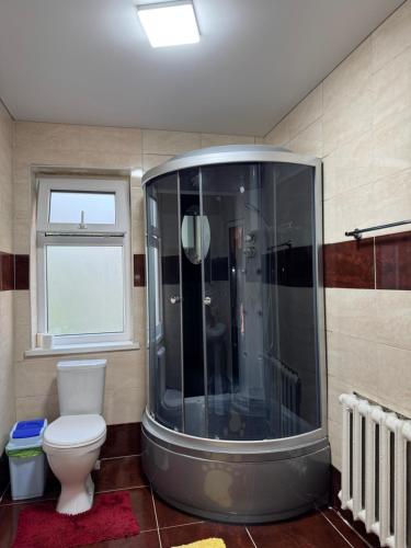 baño con ducha, aseo y ventana en Cozy, en Bishkek