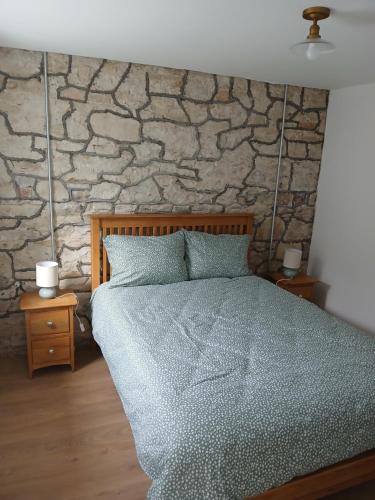 ein Schlafzimmer mit einem Bett und einer Steinwand in der Unterkunft The Widow's Cottage in Tipperary