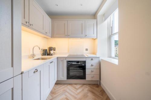a kitchen with white cabinets and a sink and a window at Beautiful 1-Bed Flat with High Ceilings in Bath