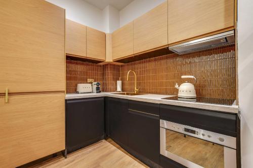 BEAUFITUL APMT - AC -2BR-6P- NOTRE DAME في باريس: مطبخ صغير مع دواليب خشبية ومغسلة