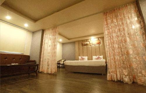 a hotel room with a bed and a couch and curtains at Palette Hotel and Resort Kankarbagh Main Road Formerly Aalcajars Inn in Bankipur