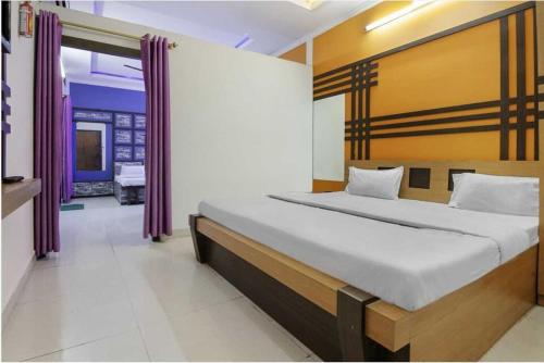a bedroom with a large bed with purple curtains at Hotel O Three Lamps Junction Vizianagaram in Vizianagram City