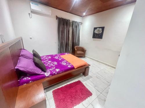 a bedroom with a bed with purple sheets and a chair at Maison Meublé de 3 CH Essos in Yaoundé