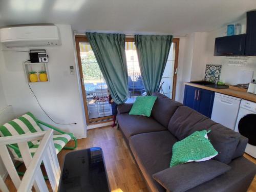 Duplex Climatisé 2chambres Centre Historique في فريجوس: غرفة معيشة مع أريكة بنية ومطبخ