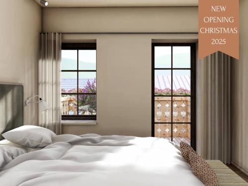 a bedroom with a white bed and two windows at Karls Design Apartments Mittenwald in Mittenwald
