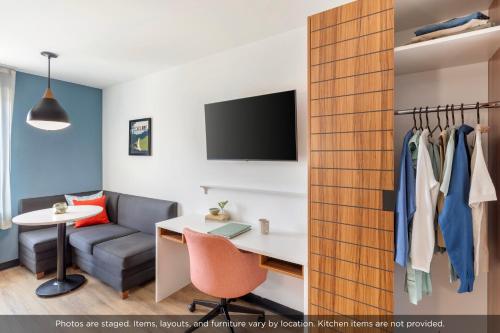 a room with a couch and a desk and a tv at Uptown Suites Extended Stay Denver CO -Westminster in Westminster