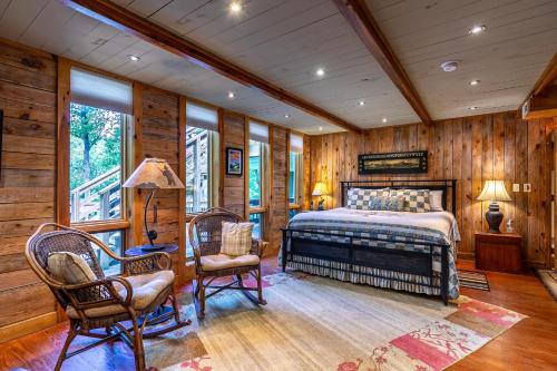 a bedroom with a bed and chairs and wooden walls at A River Mist in Sugar Grove