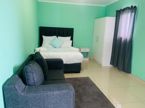 a bedroom with a bed and a couch and a chair at The Columbine Couples Suite in Swakopmund
