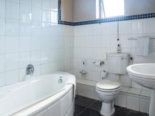 a bathroom with a tub and a toilet and a sink at Harewood Lodge in East London
