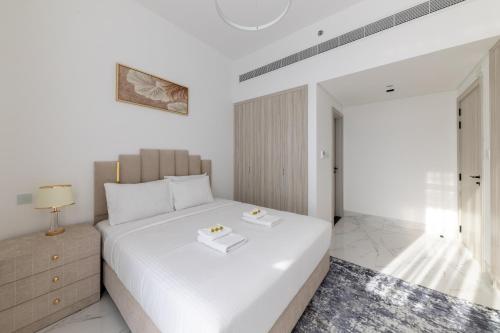 a bedroom with a white bed and a nightstand at Brand New Grand 2BR Duplex apartment in Jumeirah Village Circle with Pool, Gym and kids playground in Dubai