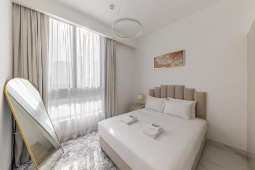 a white bedroom with a large bed and a window at Brand New Grand 2BR Duplex apartment in Jumeirah Village Circle with Pool, Gym and kids playground in Dubai