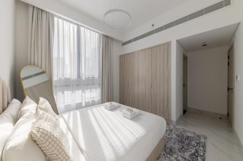 a bedroom with a white bed and a large window at Brand New Grand 2BR Duplex apartment in Jumeirah Village Circle with Pool, Gym and kids playground in Dubai