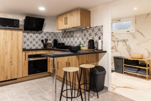 a kitchen with wooden cabinets and bar stools at locations Spa chez corinne et gilles in Marlenheim